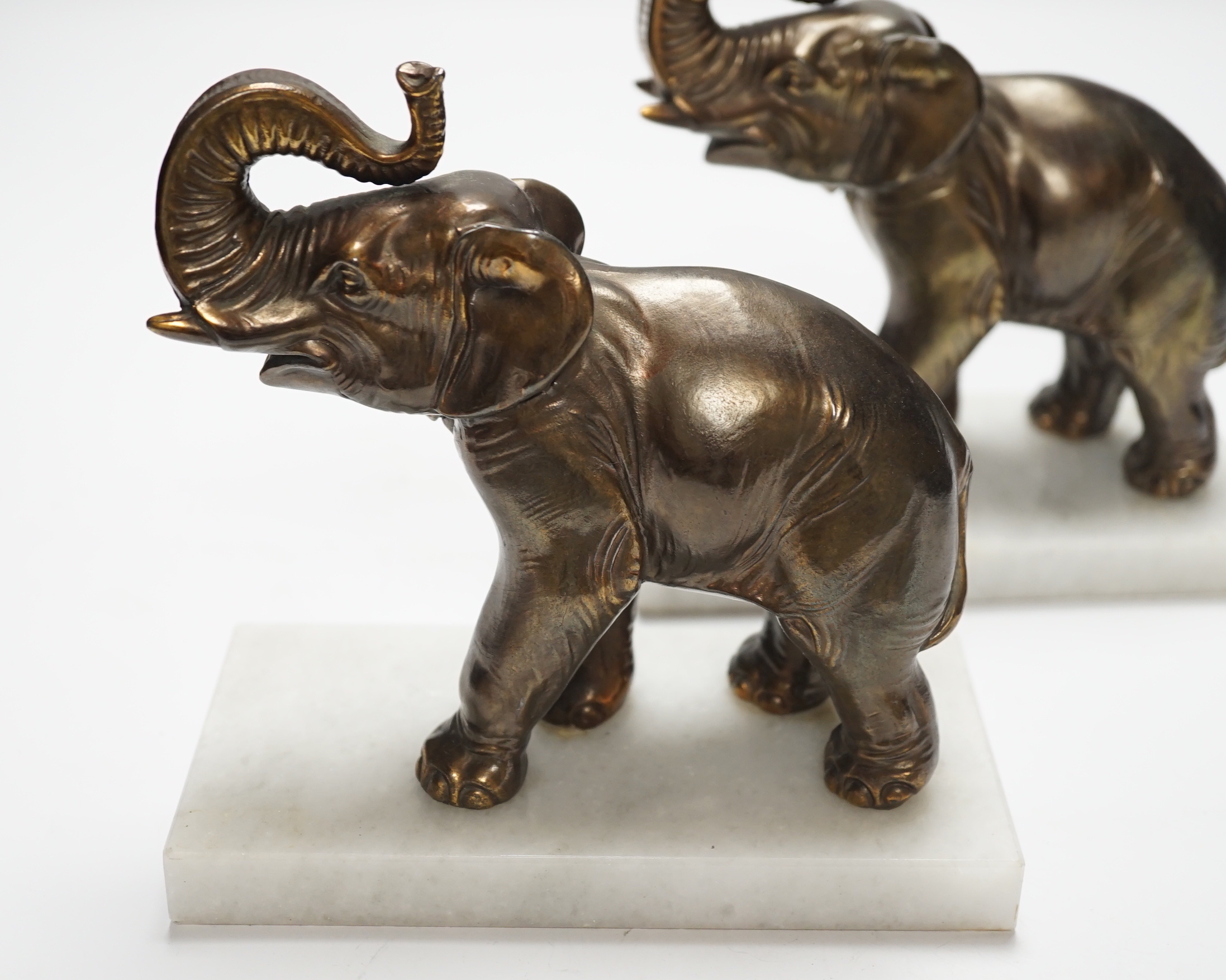 A pair of cast metal elephants on marble bases, 15.5cm high